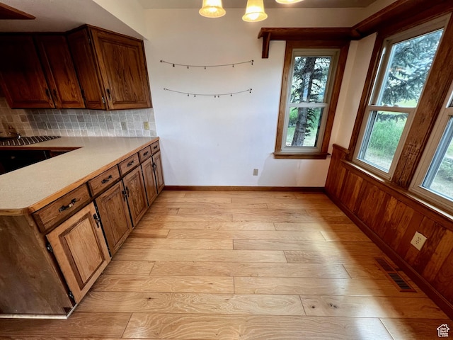 1752 Cedar View Rd, Soda Springs, ID 83276 - kitchen featuring light wood finished floors, backsplash, light countertops, brown cabinetry, and a wainscoted wall