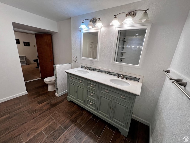 1752 Cedar View Rd, Soda Springs, ID 83276 - bathroom featuring wood finished floors, toilet, double vanity, a textured wall, and a tile shower