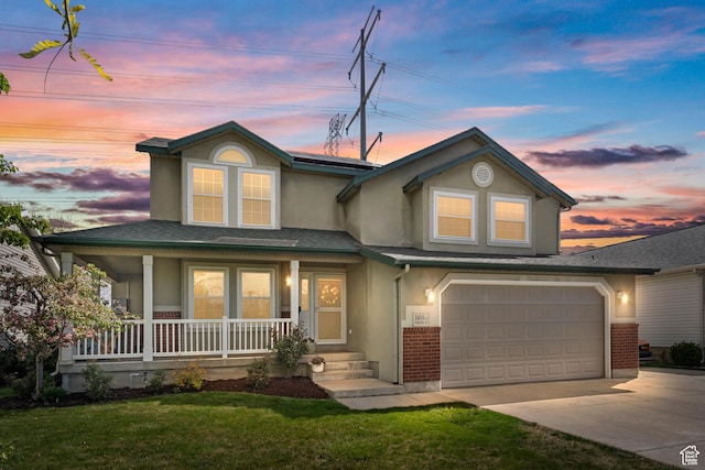 view of front of property featuring a garage, stucco siding, a porch, a lawn, and driveway