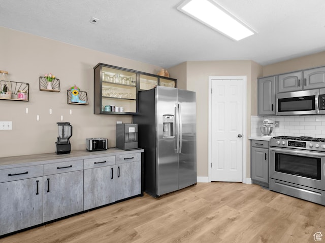 1415 S Bridgeview Dr W, Layton, UT 84041 - kitchen featuring light wood-style floors, light countertops, gray cabinets, stainless steel appliances, and tasteful backsplash