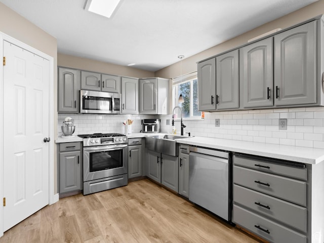 1415 S Bridgeview Dr W, Layton, UT 84041 - kitchen featuring a sink, light wood-style floors, gray cabinets, stainless steel appliances, and tasteful backsplash