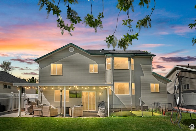 1415 S Bridgeview Dr W, Layton, UT 84041 - back of property at dusk with a trampoline, a fenced backyard, an outdoor living space, a lawn, and a patio