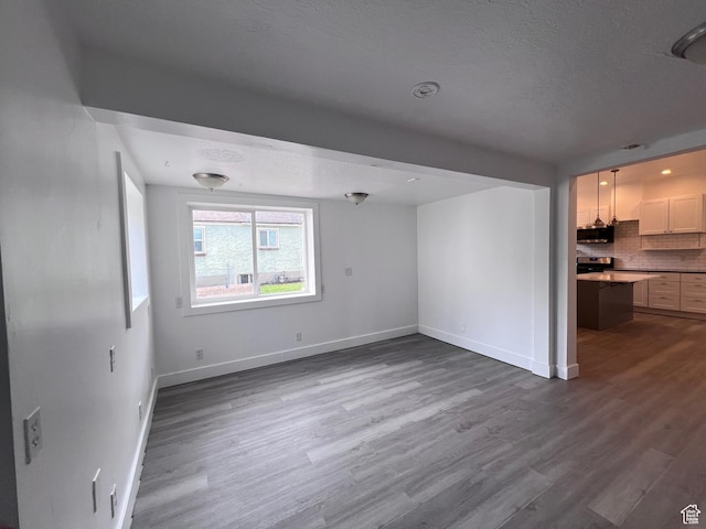 172 N 300 W, Logan, UT 84321 - unfurnished living room featuring baseboards, a textured ceiling, and wood finished floors