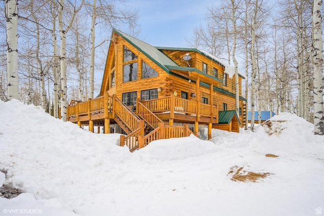 snow covered house featuring a wooden deck