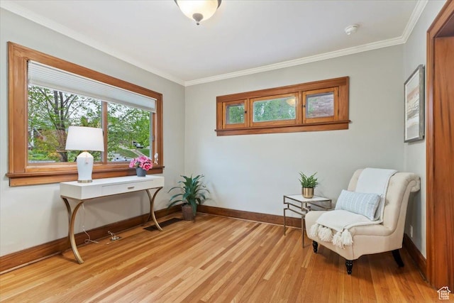 living area featuring crown molding, baseboards, and light wood finished floors