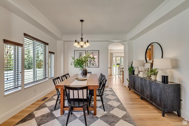 3381 W Slate View Dr, South Jordan, UT 84095 - dining area featuring a healthy amount of sunlight, arched walkways, light wood-style flooring, and a notable chandelier