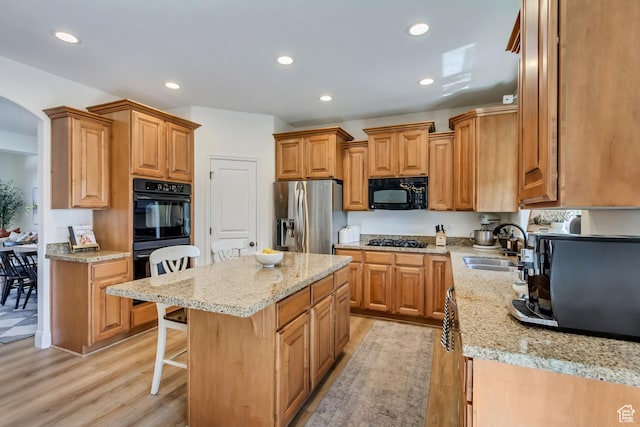 3381 W Slate View Dr, South Jordan, UT 84095 - kitchen with a sink, black appliances, a kitchen bar, and light wood-style flooring