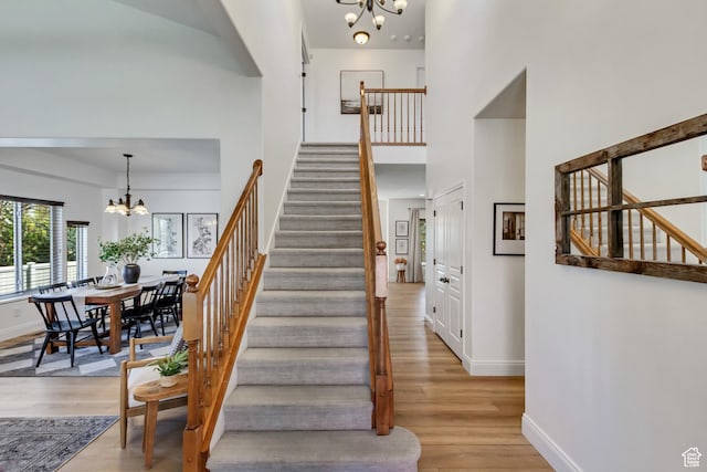 3381 W Slate View Dr, South Jordan, UT 84095 - staircase with baseboards, a towering ceiling, wood finished floors, and a chandelier