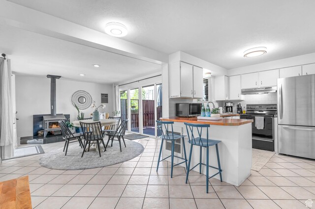 6888 S 455 E, Midvale, UT 84047 - kitchen with decorative backsplash, a breakfast bar area, wooden counters, appliances with stainless steel finishes, and under cabinet range hood