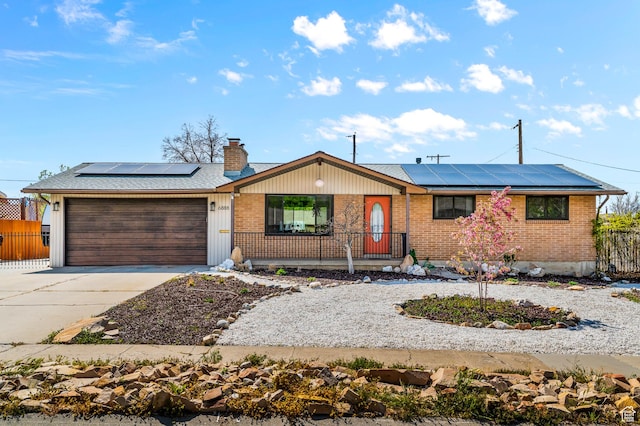 6888 S 455 E, Midvale, UT 84047 - ranch-style home with covered porch, brick siding, roof mounted solar panels, concrete driveway, and an attached garage