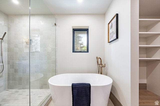 2568 E Sherwood Dr, Salt Lake City, UT 84108 - bathroom with wood finished floors, baseboards, a freestanding bath, built in shelves, and a stall shower