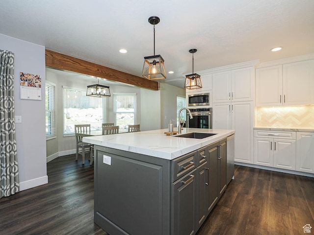 kitchen featuring a kitchen island with sink, gray cabinets, white cabinets, a sink, and stainless steel appliances