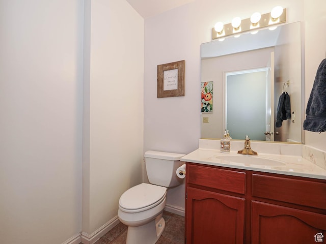 half bath featuring baseboards, vanity, and toilet