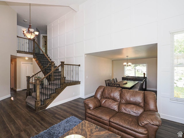 living area with an inviting chandelier, a towering ceiling, a wealth of natural light, and stairway