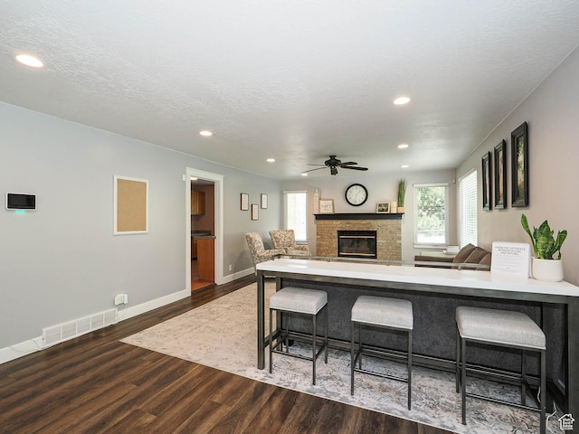living room featuring ceiling fan, visible vents, wood finished floors, a glass covered fireplace, and recessed lighting