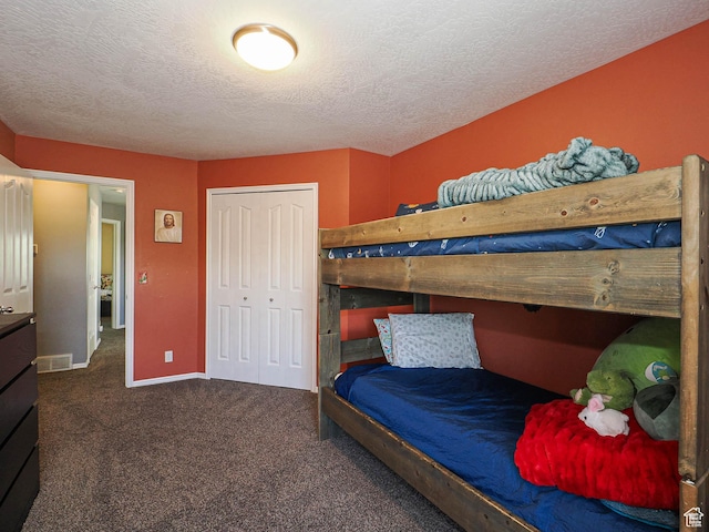 carpeted bedroom featuring a closet, a textured ceiling, and baseboards