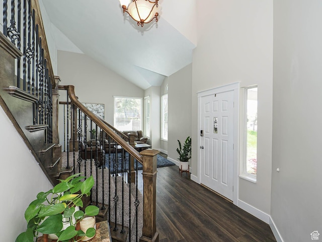 foyer entrance with baseboards, high vaulted ceiling, wood finished floors, and stairway