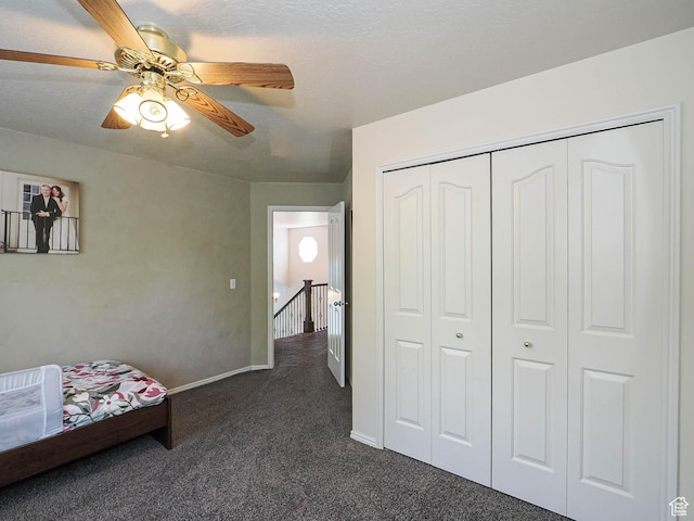 bedroom with a ceiling fan, baseboards, dark carpet, and a closet