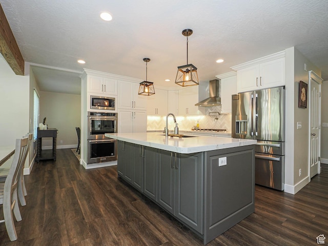 kitchen featuring baseboards, wall chimney range hood, a sink, appliances with stainless steel finishes, and gray cabinetry