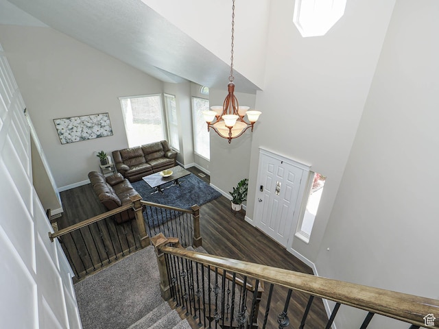 stairway with an inviting chandelier, baseboards, wood finished floors, and high vaulted ceiling