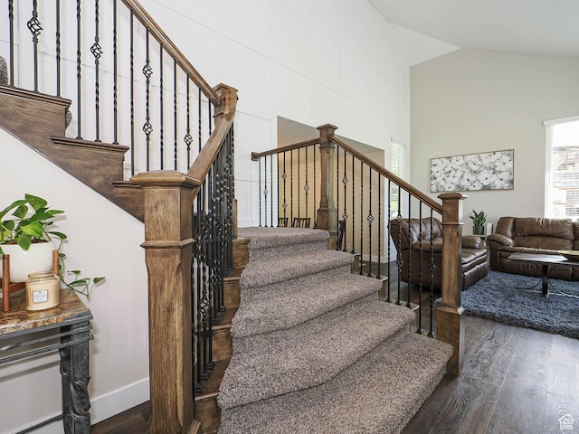 staircase featuring baseboards, wood finished floors, and lofted ceiling
