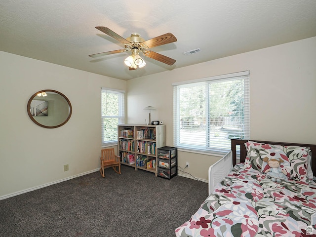 bedroom with baseboards, visible vents, multiple windows, and dark colored carpet