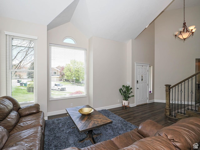 living room with a chandelier, a wealth of natural light, wood finished floors, and stairway