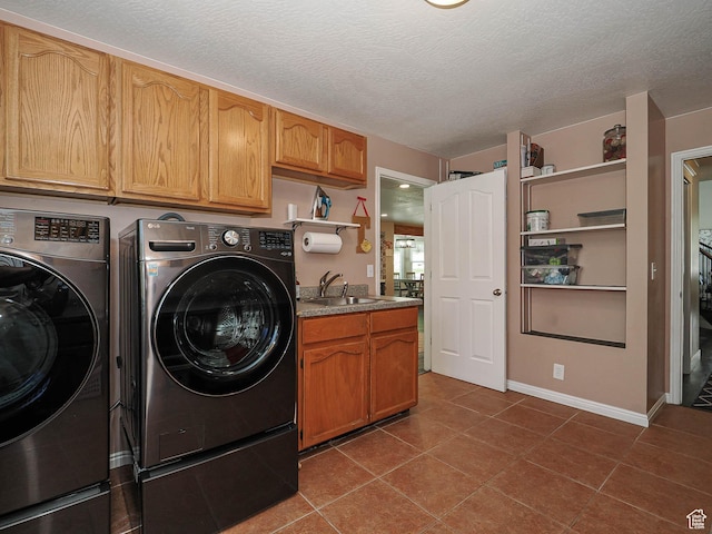 washroom featuring a sink, a textured ceiling, cabinet space, and washing machine and clothes dryer