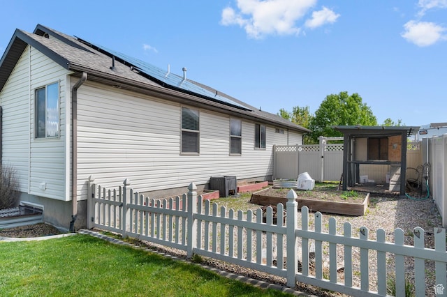2135 N 130 W, Tooele, UT 84074 - back of property featuring cooling unit, a fenced backyard, a vegetable garden, a yard, and solar panels