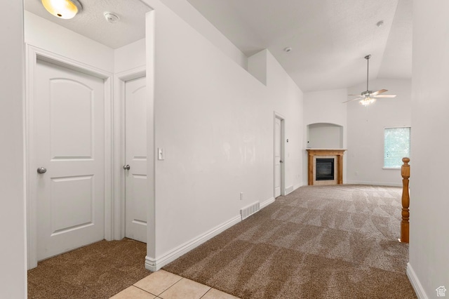 2135 N 130 W, Tooele, UT 84074 - unfurnished living room with visible vents, a glass covered fireplace, carpet, a ceiling fan, and vaulted ceiling
