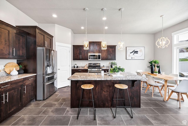 590 S 1030 E, Smithfield, UT 84335 - kitchen with a breakfast bar area, appliances with stainless steel finishes, light stone countertops, dark brown cabinets, and an island with sink