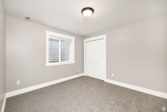 590 S 1030 E, Smithfield, UT 84335 - unfurnished bedroom with baseboards, a closet, dark colored carpet, and visible vents