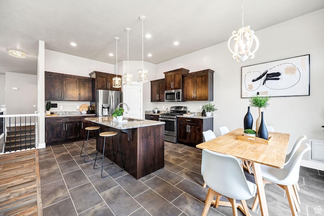 590 S 1030 E, Smithfield, UT 84335 - kitchen featuring dark brown cabinetry, a kitchen bar, appliances with stainless steel finishes, a sink, and an island with sink