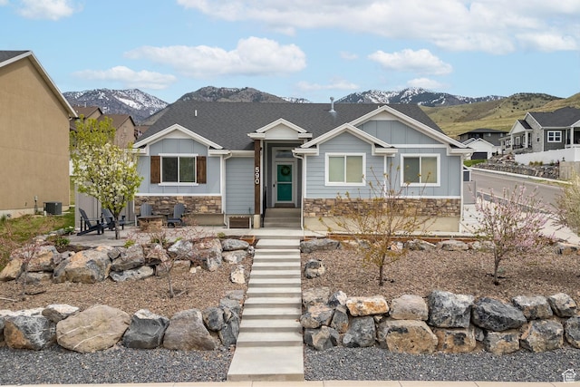 view of front of property with fence, stone siding, board and batten siding, a mountain view, and central air condition unit