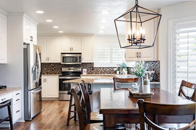 10944 S Surrey Meadow Cv, South Jordan, UT 84095 - kitchen with stainless steel appliances, a chandelier, healthy amount of natural light, wood finished floors, and recessed lighting