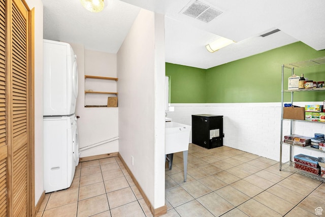 811 S Park Ave W, Logan, UT 84321 - interior space featuring laundry area, wainscoting, stacked washing maching and dryer, light tile patterned floors, and visible vents