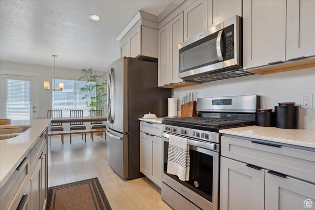 4101 W 1850 N, Lehi, UT 84043 - kitchen featuring an inviting chandelier, a textured ceiling, light wood finished floors, hanging light fixtures, and stainless steel appliances