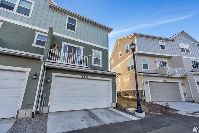 view of front of property with an attached garage, board and batten siding, a balcony, and driveway