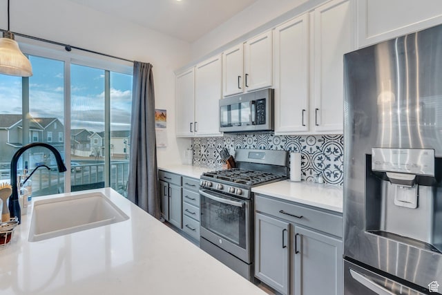 kitchen featuring decorative backsplash, pendant lighting, light countertops, a sink, and stainless steel appliances