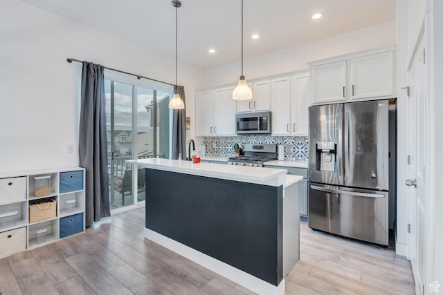 kitchen with light countertops, stainless steel appliances, decorative backsplash, and light wood-style floors