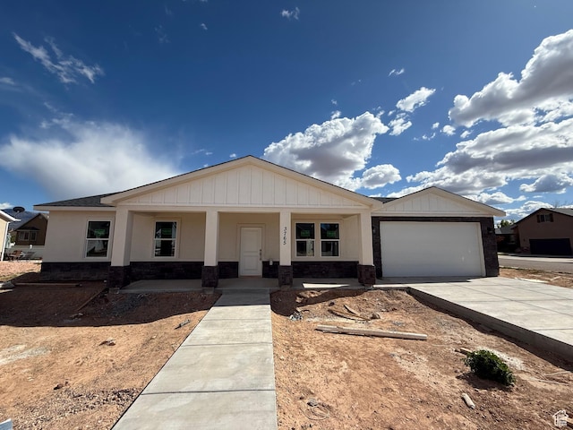 ranch-style home with an attached garage, concrete driveway, a porch, and stone siding