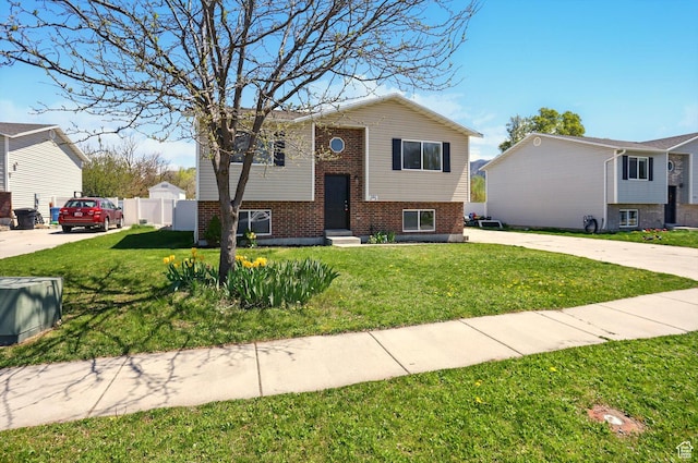 680 S Riverwalk Pkwy W, Logan, UT 84321 - raised ranch with concrete driveway, brick siding, fence, and a front lawn