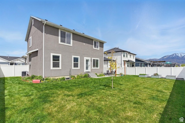 2471 W Anne Ave, West Haven, UT 84401 - back of property featuring cooling unit, a mountain view, a fenced backyard, a yard, and stucco siding