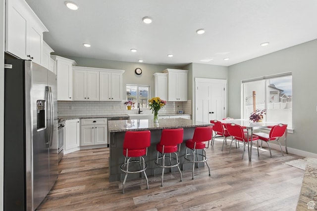 2471 W Anne Ave, West Haven, UT 84401 - kitchen with a kitchen island, appliances with stainless steel finishes, dark stone countertops, light wood-style floors, and white cabinetry