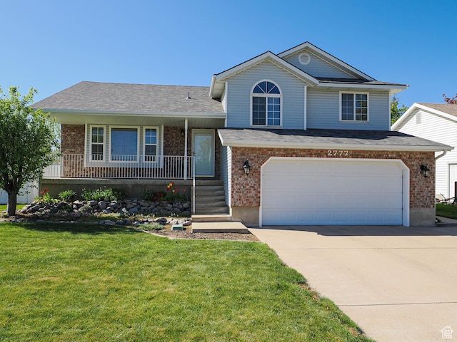 tri-level home featuring a front yard, concrete driveway, a porch, and brick siding