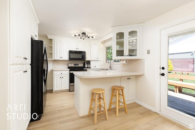 970 N 500 E, Pleasant Grove, UT 84062 - kitchen featuring white cabinets, black appliances, light wood finished floors, a peninsula, and glass insert cabinets