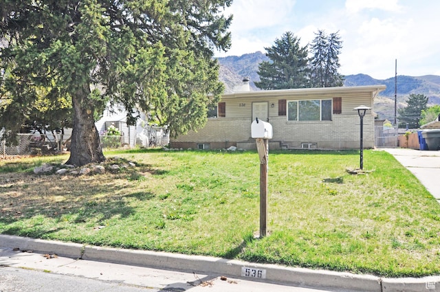 536 S Brinker E, Ogden, UT 84404 - view of front facade featuring fence, a mountain view, a front lawn, and brick siding