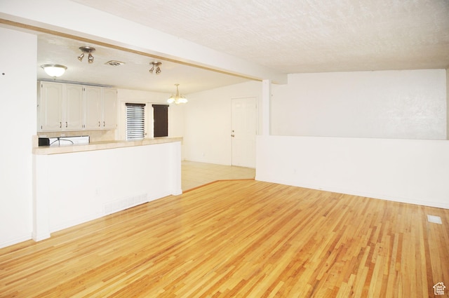 536 S Brinker E, Ogden, UT 84404 - interior space with light wood-type flooring, a textured ceiling, a chandelier, and visible vents