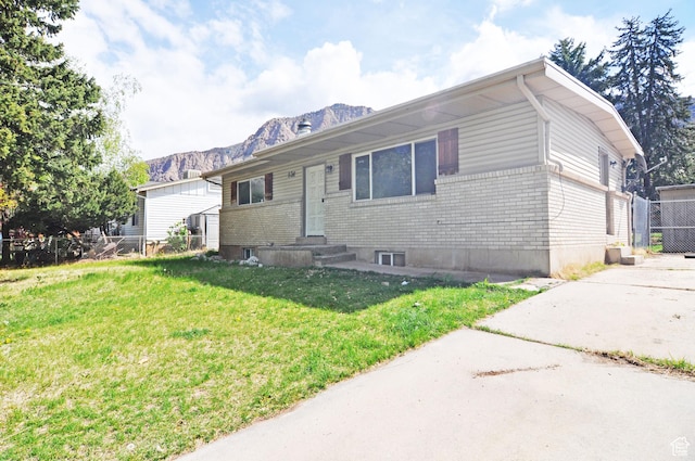 536 S Brinker E, Ogden, UT 84404 - view of front of house with brick siding, fence, a mountain view, and a front lawn