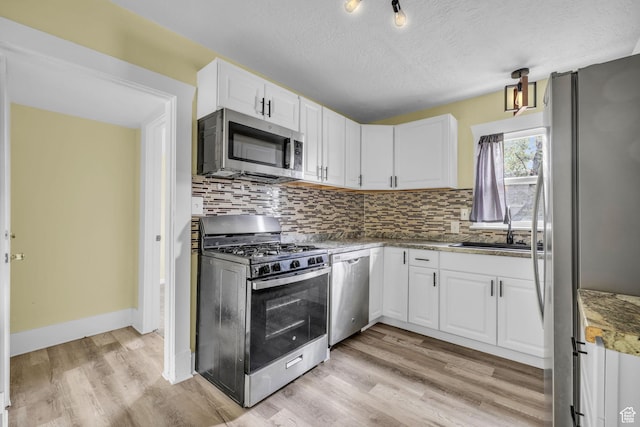 3485 S Grant Ave, Ogden, UT 84403 - kitchen with appliances with stainless steel finishes, tasteful backsplash, a sink, light wood finished floors, and white cabinetry